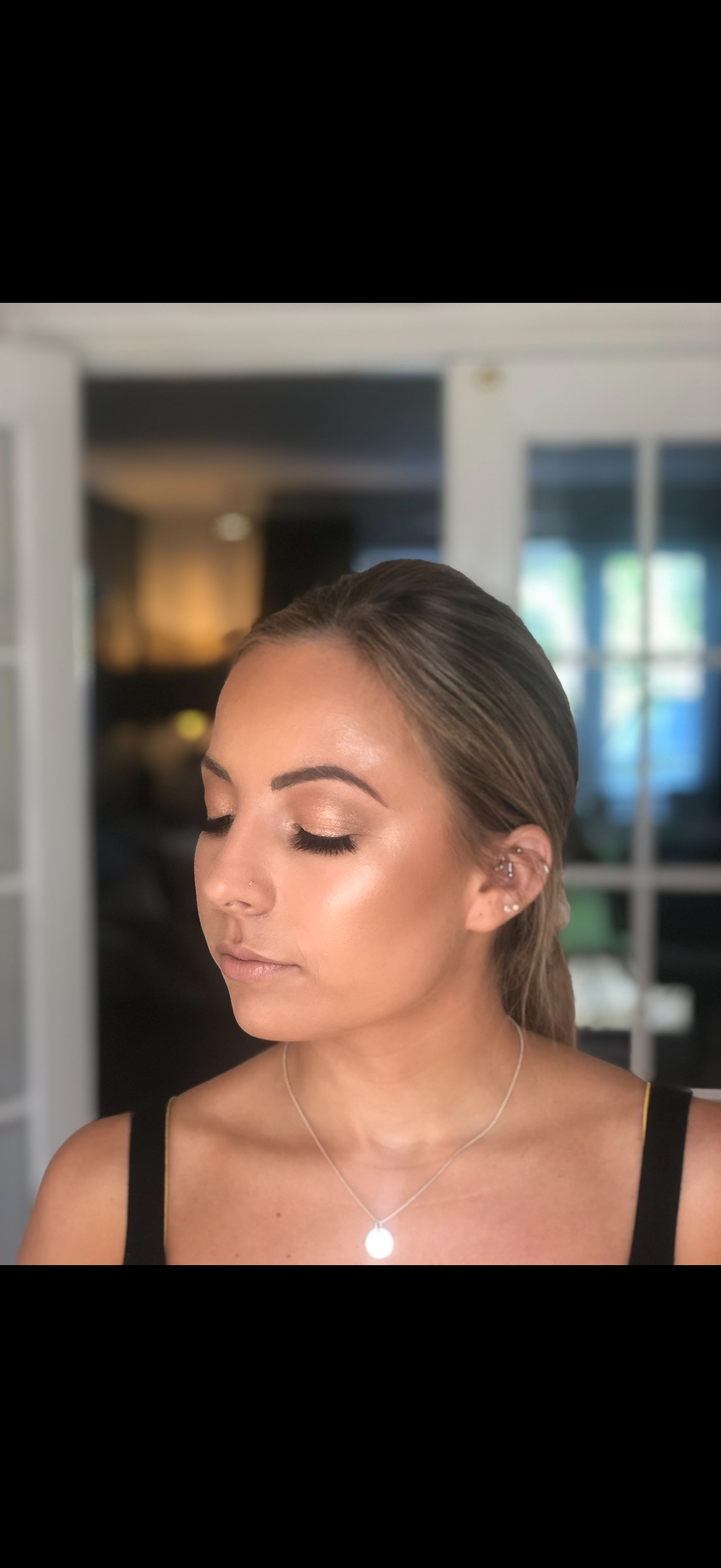 Client looking down to show soft neutral eyeshadow and luminous skin